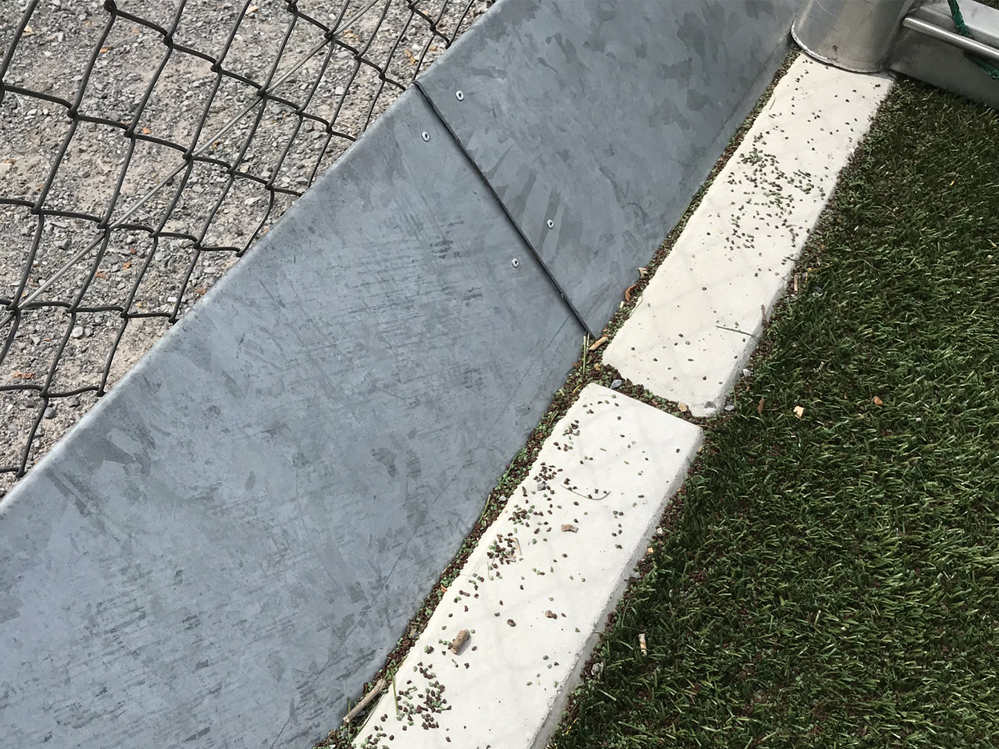 Umlaufende Bleche an Kunstrasenplätzen können Infill zurückhalten. Umlaufendes Blech zum Rückhalt von Infill.