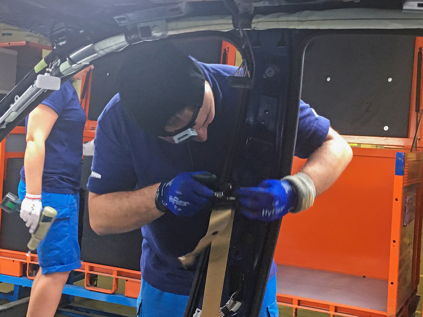 Production employee during bodywork assembly: a newly developed sensor module on the cap to record light consumption, ambient temperature and blue light component over the course of the shift.